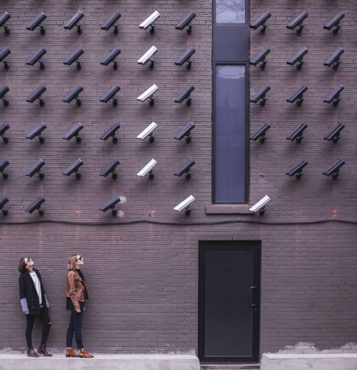 Two people looking up at a wall of security cameras